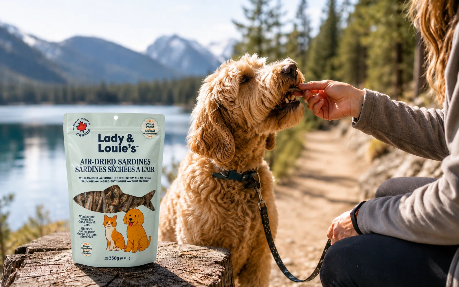 Dog receiving a Lady and Louie's sardine treat beside a mountain lake